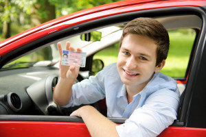 Teenager sitting in new car and shows his drivers license